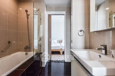 Modern bathroom with sleek design and bathtub, leading to a cozy bedroom.