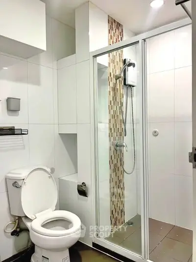 Modern bathroom with glass shower enclosure and sleek white tiles.