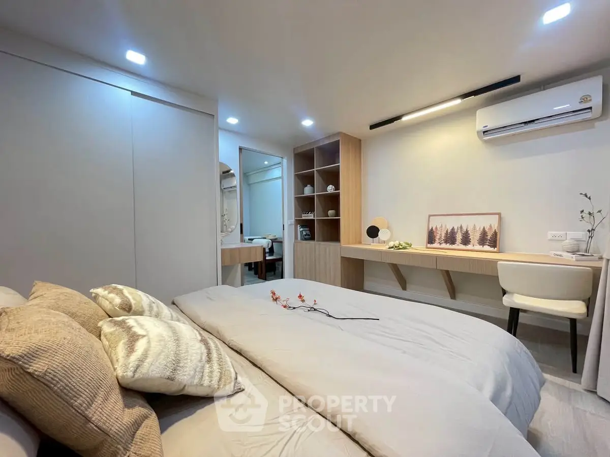 Modern bedroom with stylish decor and workspace, featuring cozy bedding and elegant lighting.