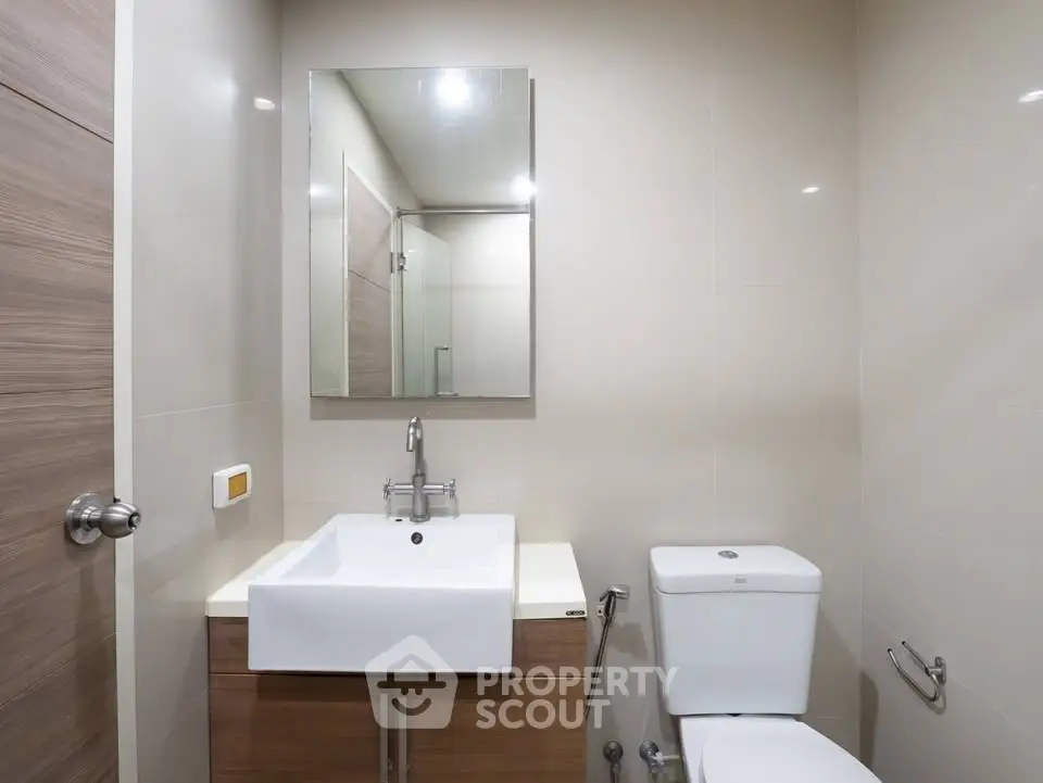 Modern bathroom with sleek fixtures and minimalist design, featuring a stylish sink and toilet.