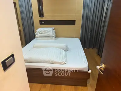 Cozy bedroom with modern design and wooden flooring, featuring a comfortable bed and elegant curtains.