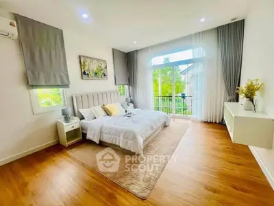 Spacious bedroom with elegant decor and large windows opening to a scenic balcony view.