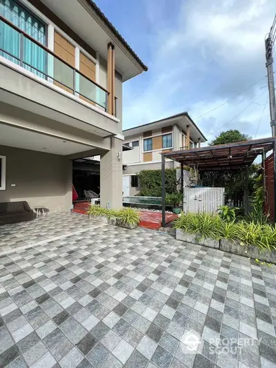 Modern two-story house with spacious tiled driveway and lush garden