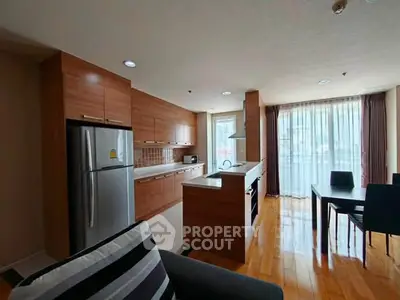 Modern kitchen with wooden cabinets and dining area in open layout apartment.