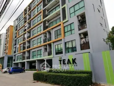Modern apartment building exterior with balconies and parking area.