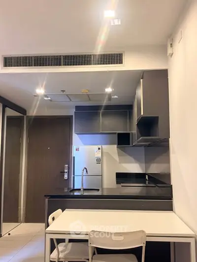 Modern kitchen with sleek cabinetry and dining area in a contemporary apartment.