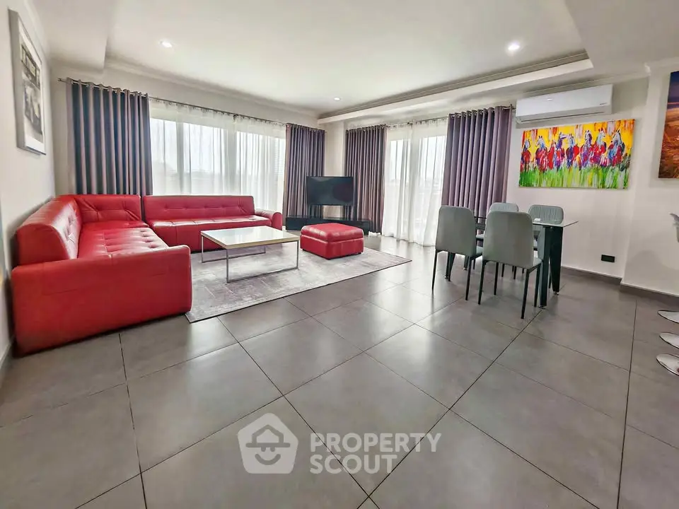 Spacious modern living room with red sectional sofa and dining area, perfect for entertaining.