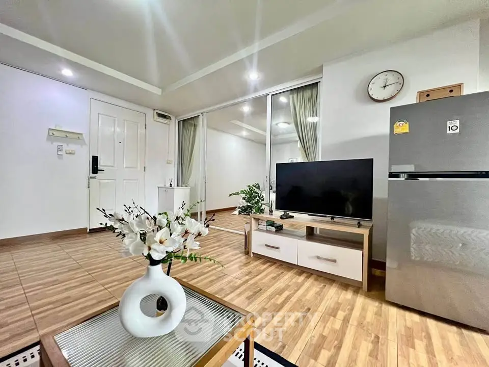 Modern living room with sleek decor, TV, and fridge, showcasing stylish interior design.