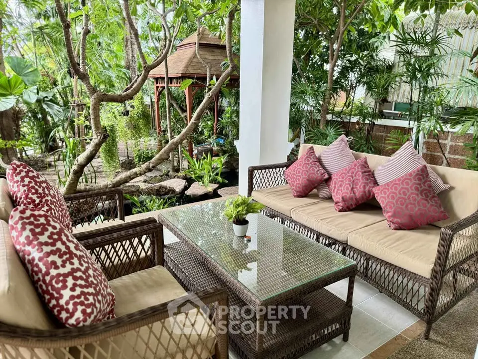 Charming garden patio with cozy wicker furniture and lush greenery, perfect for relaxation.