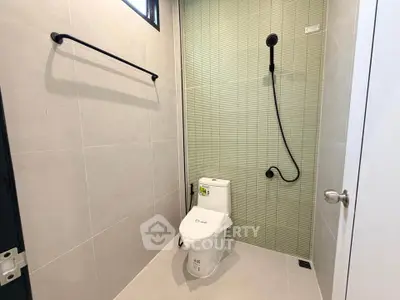 Modern bathroom with sleek design and minimalist fixtures, featuring a shower and toilet.
