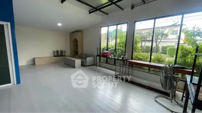Spacious living room with large windows and garden view, featuring modern decor and ample natural light.