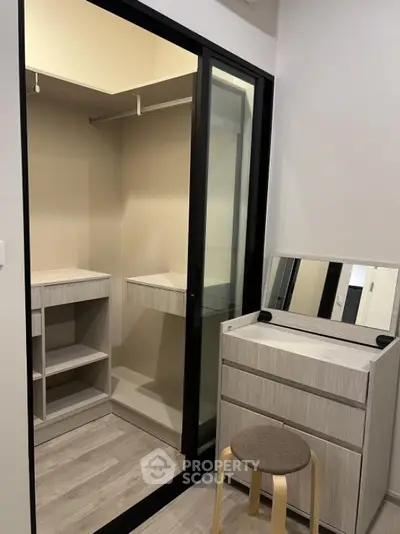 Modern walk-in closet with sliding glass doors and vanity in stylish apartment