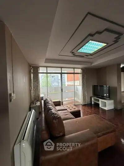 Spacious living room with modern decor and large windows opening to a balcony.