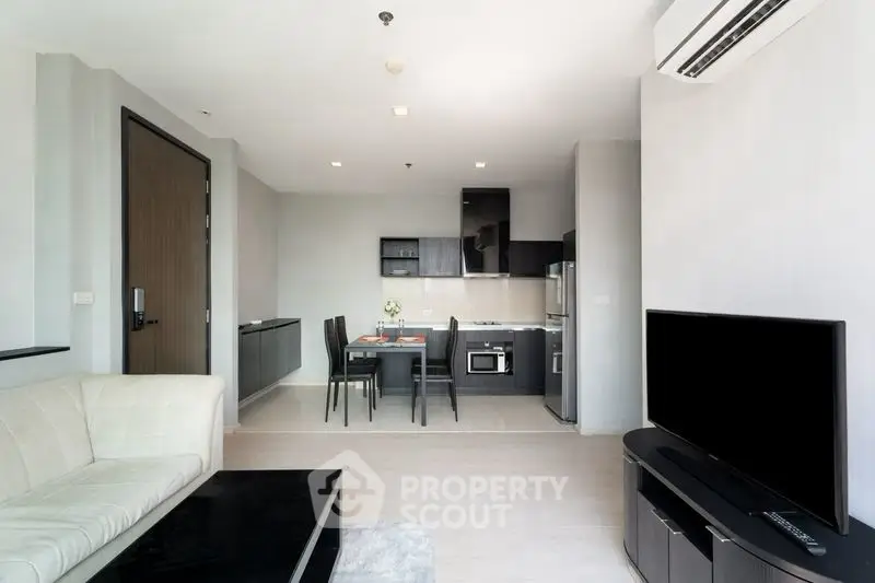 Modern open-plan living room with sleek kitchen and dining area, featuring contemporary furniture and appliances.