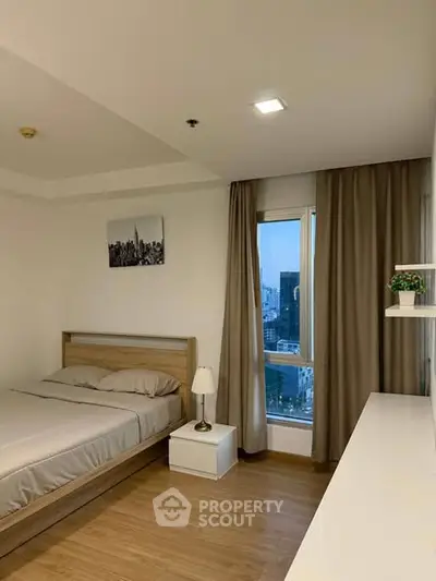 Modern bedroom with city view, wooden flooring, and elegant decor.