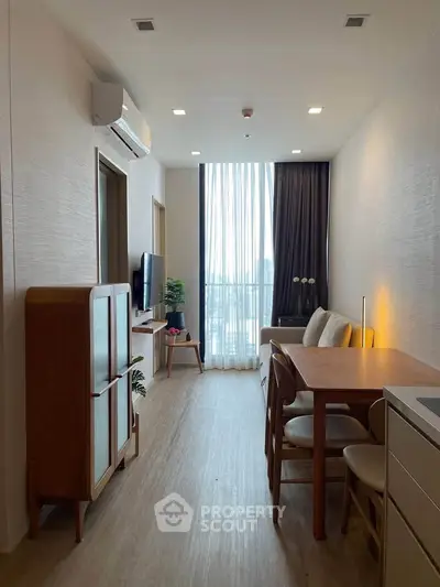 Modern living room with dining area and large window offering natural light.
