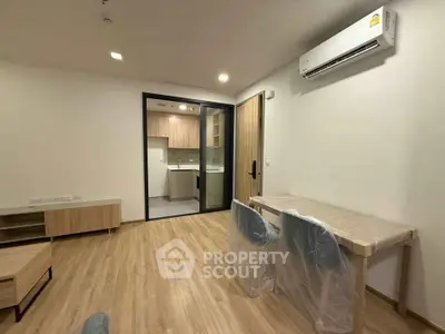 Modern living room with wooden flooring and open kitchen layout in a stylish apartment.