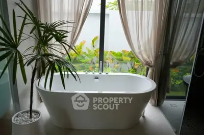 Luxurious bathroom with freestanding bathtub and garden view, perfect for relaxation.