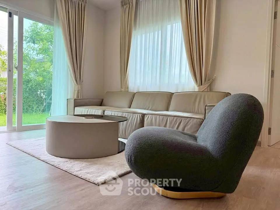 Elegant living room with modern furniture and large windows overlooking a garden.
