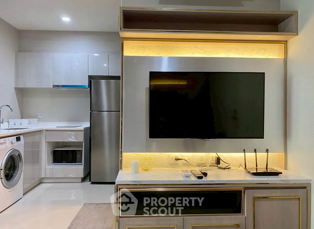 Modern living room with sleek kitchen and appliances, featuring a stylish TV setup.