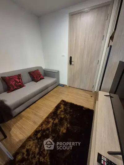 Cozy living room with modern sofa and stylish decor in a compact apartment setting.