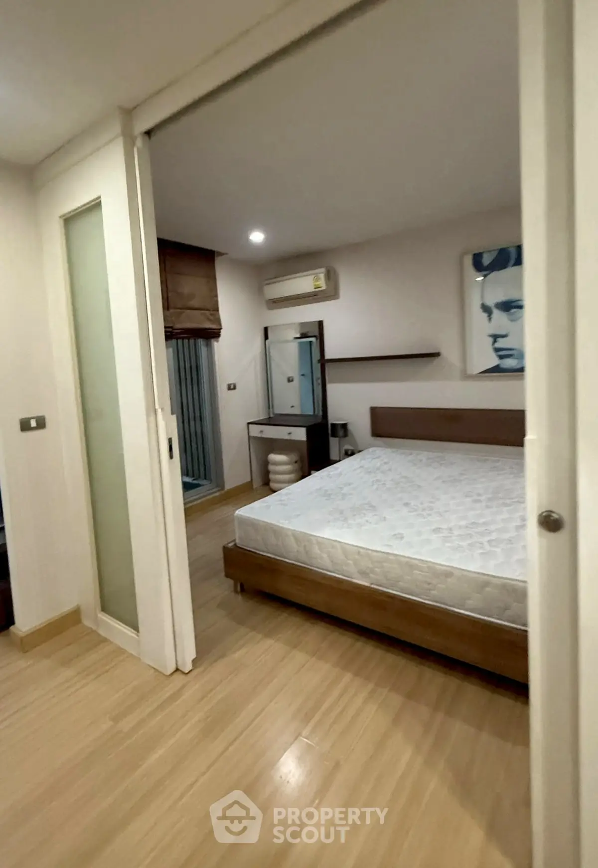 Modern bedroom with wooden flooring and stylish decor, featuring a comfortable bed and contemporary artwork.