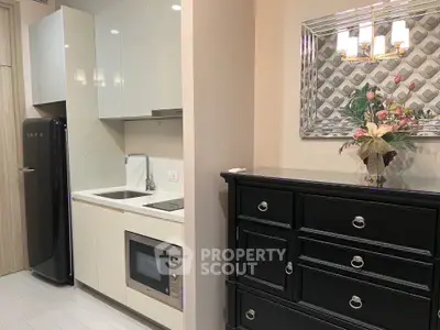 Modern compact kitchen with sleek black fridge and built-in microwave, adjacent to elegant dresser and decorative mirror.