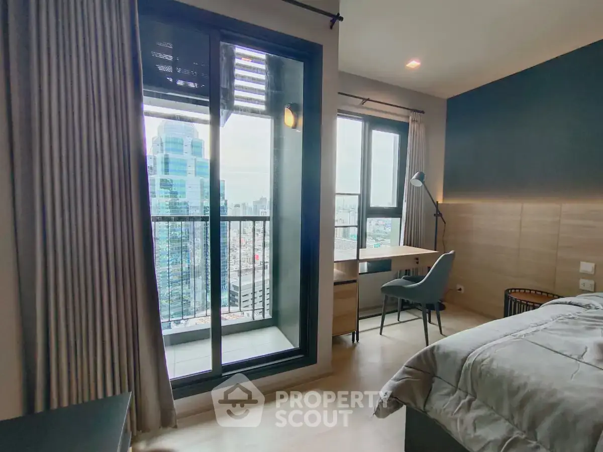 Modern bedroom with city view and workspace, featuring large windows and stylish decor.