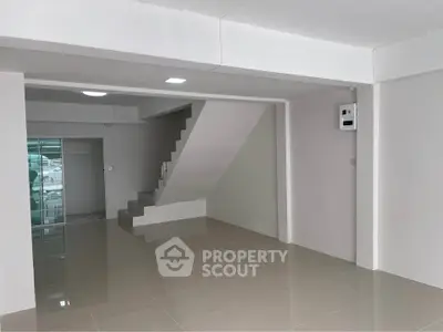 Spacious open-plan interior with modern staircase and glossy tiled flooring.