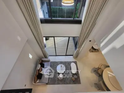 Luxurious modern living room with high ceilings and elegant decor, featuring a spacious open layout and large windows.