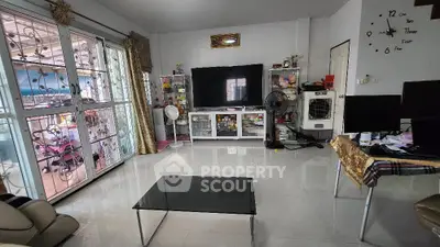 Spacious living room with modern decor and large TV, featuring a glass coffee table and balcony access.