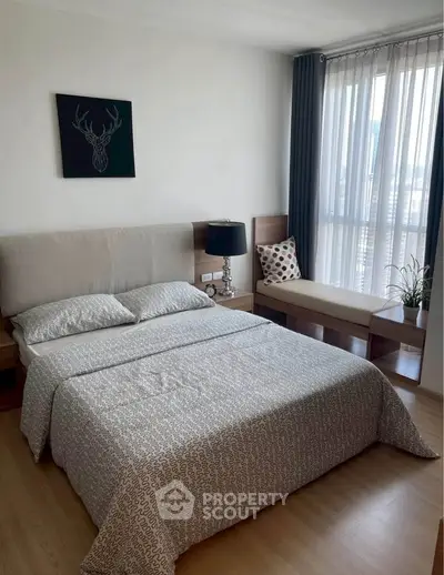 Modern bedroom with stylish decor and natural light, featuring a cozy bed and elegant furnishings.