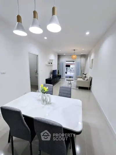 Modern open-plan living and dining area with sleek furnishings and stylish lighting.