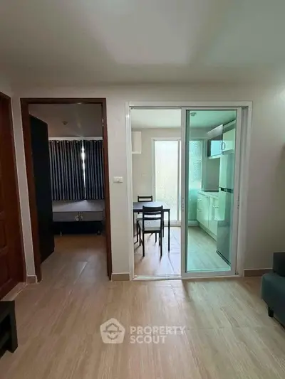 Modern apartment interior with open layout connecting living area and kitchen, featuring sleek furniture and natural light.