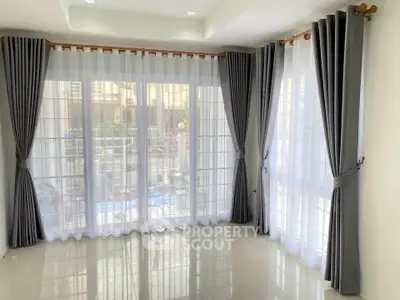 Spacious living room with large windows and elegant gray curtains