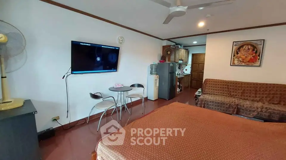 Cozy living room with TV, dining set, and kitchen area in open layout apartment.