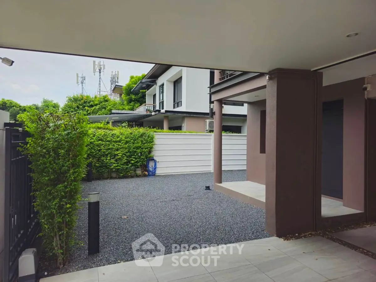 Modern house exterior with spacious driveway and lush greenery