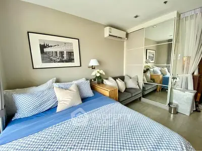 Charming bedroom with cozy decor and mirrored wardrobe in modern apartment.