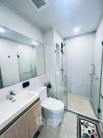 Modern bathroom with glass shower, sleek vanity, and elegant fixtures.