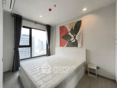 Modern bedroom with large window and city view, featuring stylish decor and natural light.