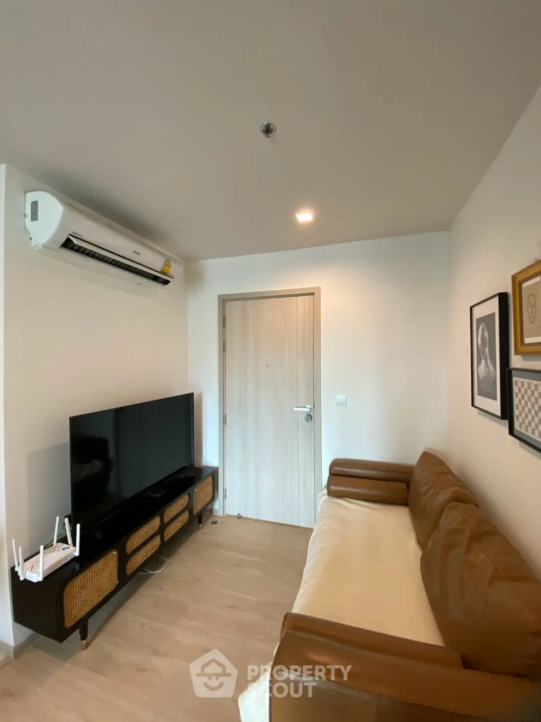 Cozy living room with modern decor, featuring a leather sofa and wall-mounted air conditioning.