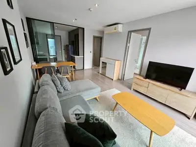 Modern living room with sleek furniture and open layout, featuring a cozy sofa and flat-screen TV.