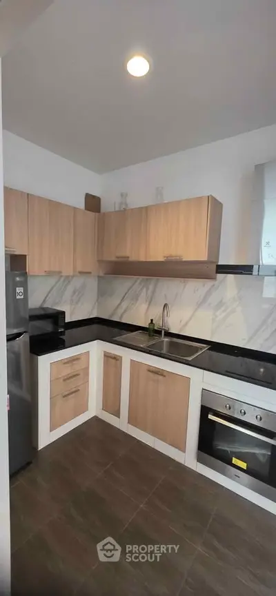 Modern kitchen with sleek cabinets, marble backsplash, and stainless steel appliances.