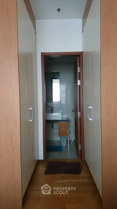 Modern bathroom entrance with wooden cabinetry and sleek design