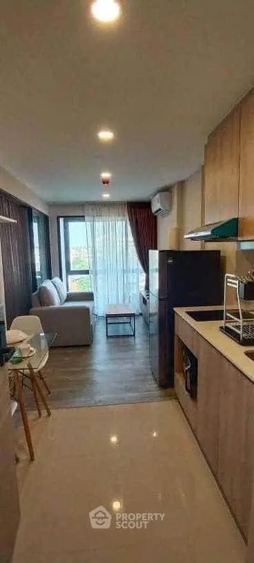 Modern open-layout living room with kitchen, featuring sleek design and natural light.