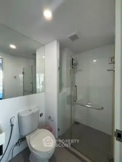 Modern bathroom with glass shower enclosure and sleek fixtures.