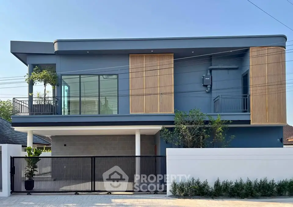 Modern two-story house with sleek design and large windows, featuring a spacious balcony and stylish facade.