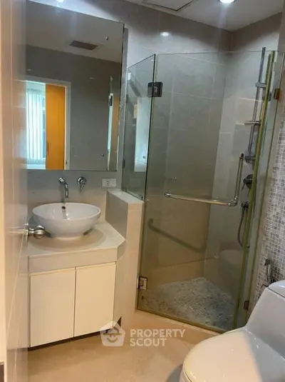 Modern bathroom with glass shower and sleek vanity in a contemporary apartment.