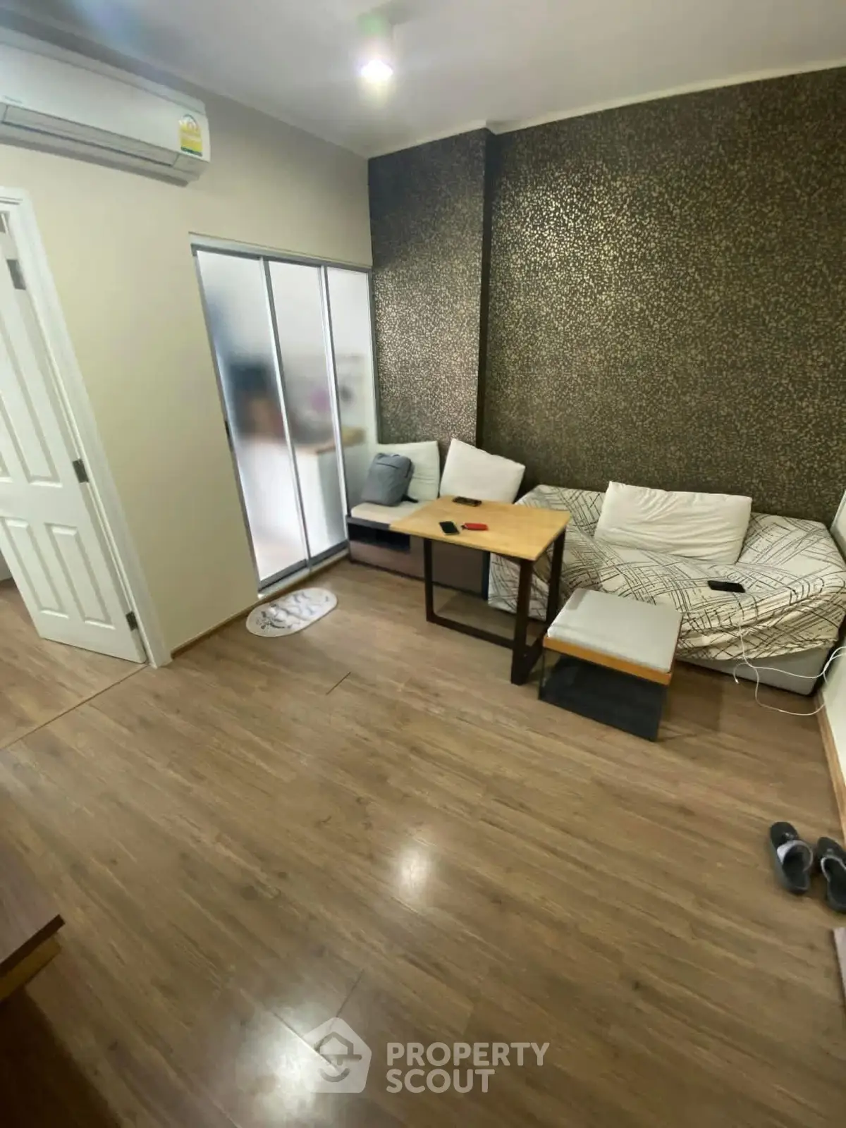 Cozy living room with modern decor and wooden flooring, featuring a comfortable sofa and stylish table.