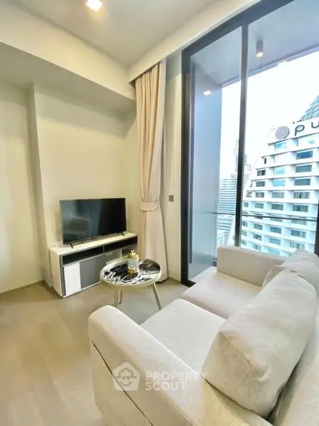 Modern living room with city view, featuring a cozy sofa and sleek TV setup.